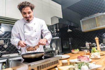 smiling-chef-frying-meat-in-restaurant-kitchen-2022-12-16-20-03-48-utc-1-905x613