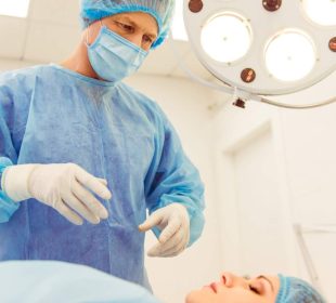 A surgeon is standing near the patient in a modern operating room, ready to perform an operation