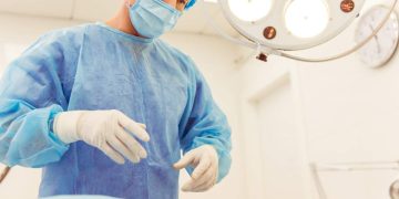 A surgeon is standing near the patient in a modern operating room, ready to perform an operation