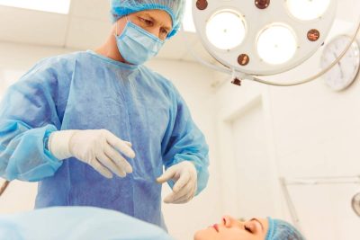 A surgeon is standing near the patient in a modern operating room, ready to perform an operation