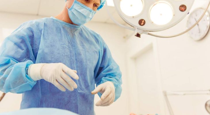 A surgeon is standing near the patient in a modern operating room, ready to perform an operation