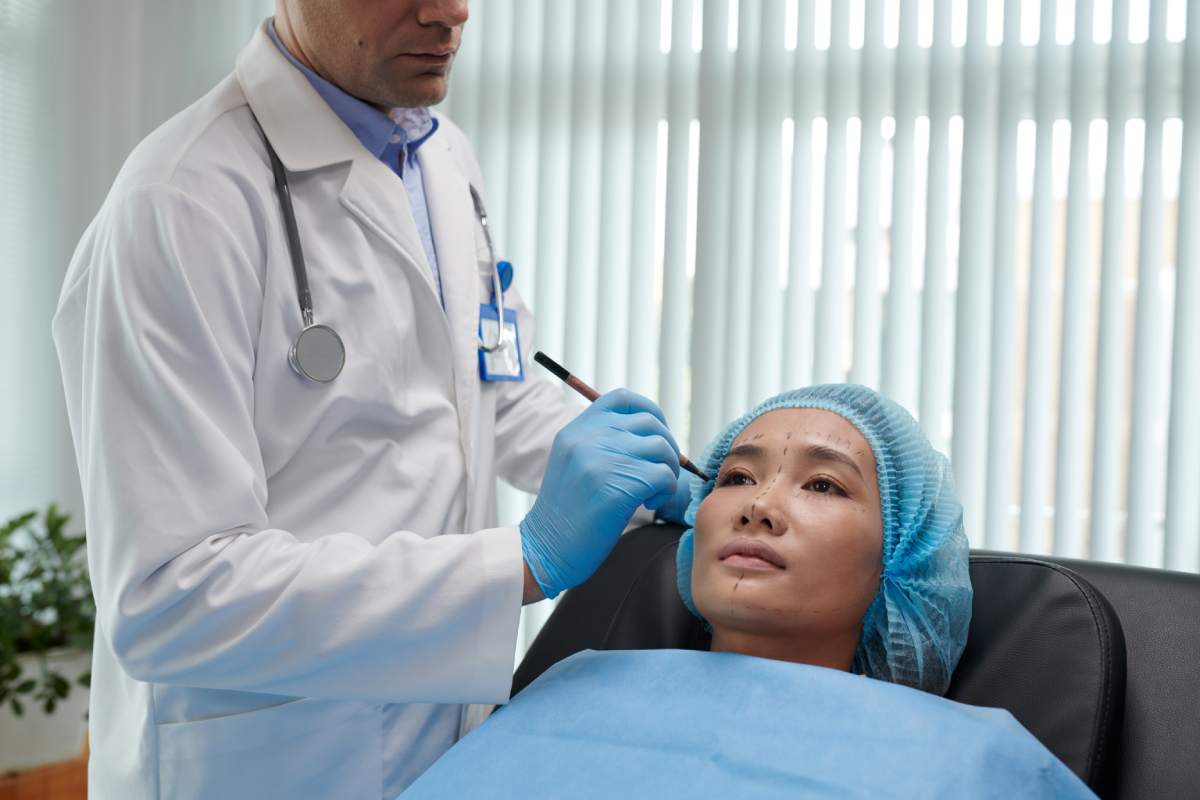 Woman sitting in chair of plastic surgeon getting her face marked