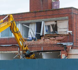 Demolition of an old building with a long reach machine hydraulic jaw. Regeneration of a space for new, modern building.