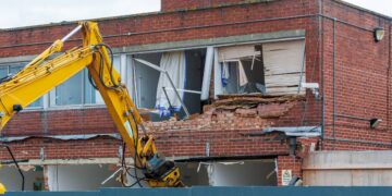 Demolition of an old building with a long reach machine hydraulic jaw. Regeneration of a space for new, modern building.