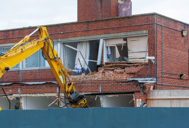Demolition of an old building with a long reach machine hydraulic jaw. Regeneration of a space for new, modern building.