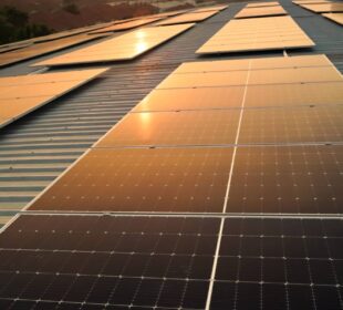 Sunset solar panel electric clean energy to the future. Solar panels on the meadow, sunset reflected on solar panel on rooftop. Green energy concept