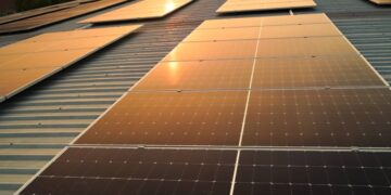 Sunset solar panel electric clean energy to the future. Solar panels on the meadow, sunset reflected on solar panel on rooftop. Green energy concept