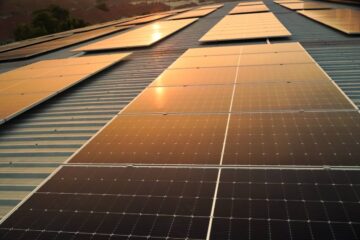 Sunset solar panel electric clean energy to the future. Solar panels on the meadow, sunset reflected on solar panel on rooftop. Green energy concept