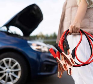close-up of a car voltmeter in the hands of a woman against the background of a broken car.