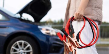 close-up of a car voltmeter in the hands of a woman against the background of a broken car.