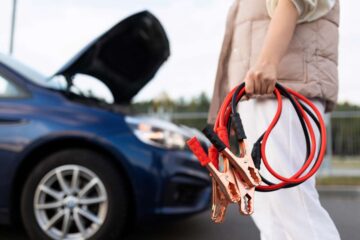 close-up of a car voltmeter in the hands of a woman against the background of a broken car.