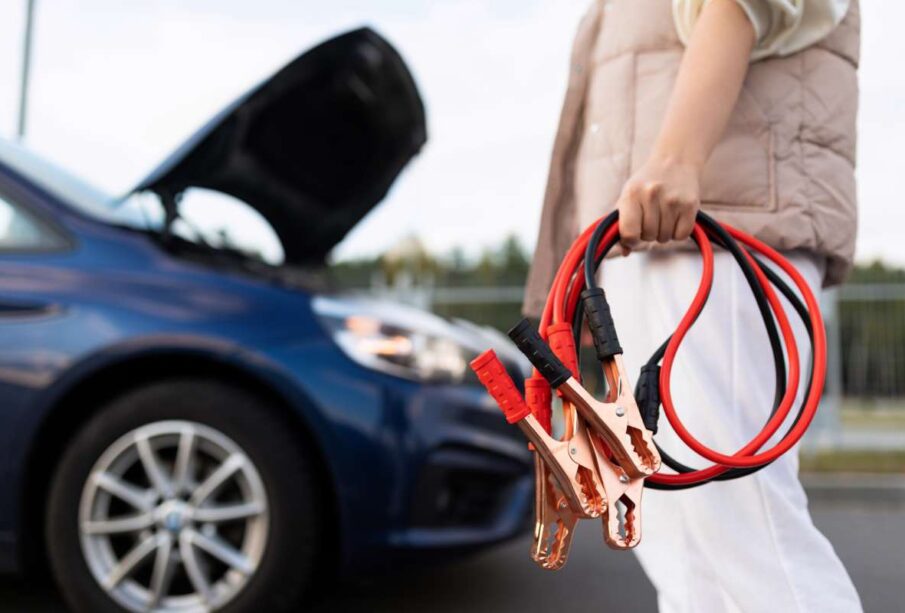 close-up of a car voltmeter in the hands of a woman against the background of a broken car.