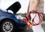 close-up of a car voltmeter in the hands of a woman against the background of a broken car.